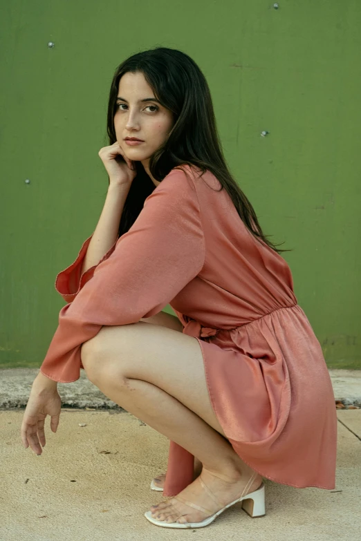 a woman sits on the floor in front of a wall