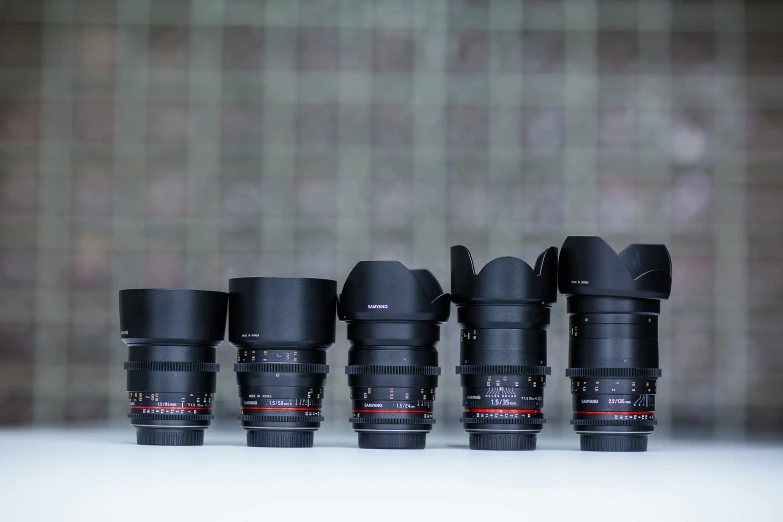 five small camera lenses lined up on a counter