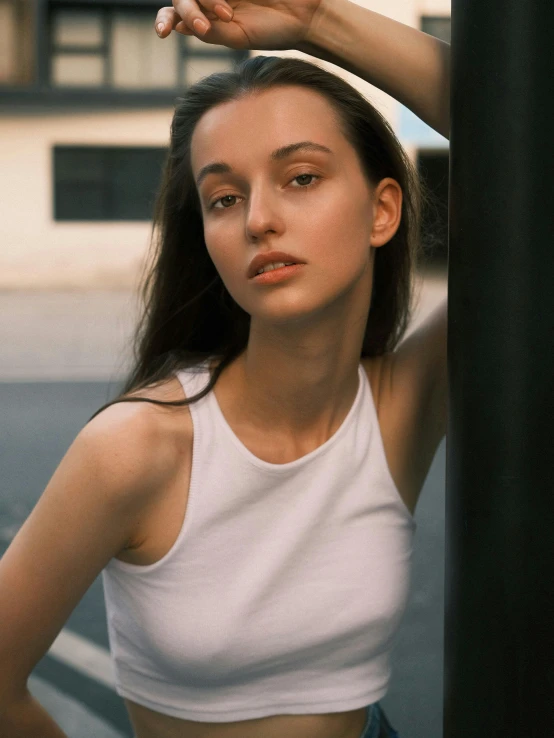 a young woman leaning against a pole on the side of a street