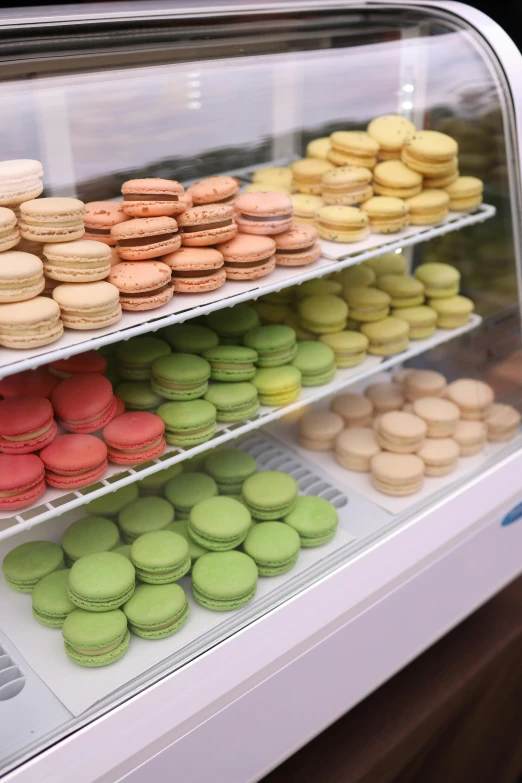 assorted colored macaroons are displayed in a deli