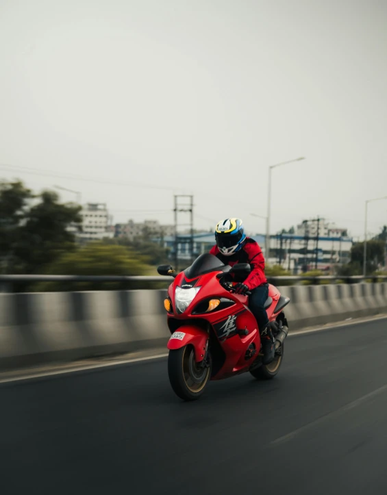 a person in helmet and red jacket rides a red motorcycle