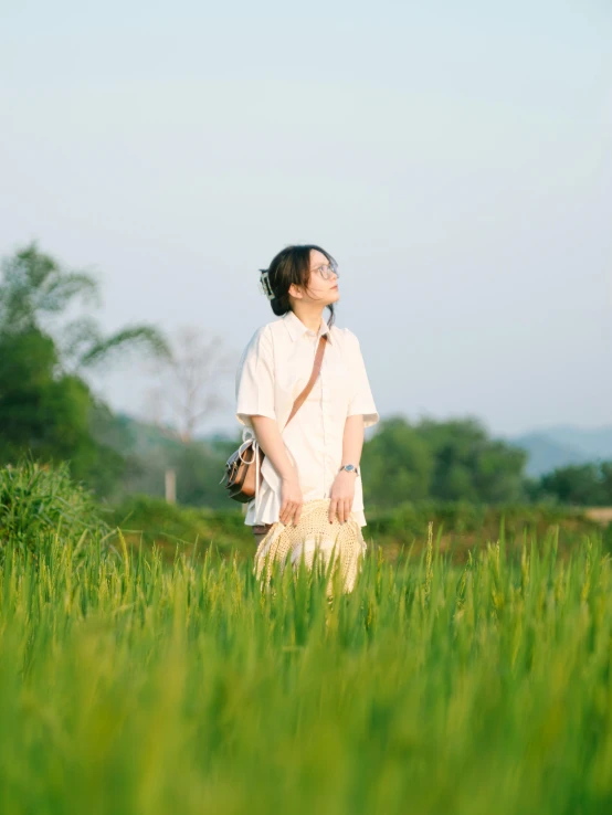 a woman standing in a field with tall green grass