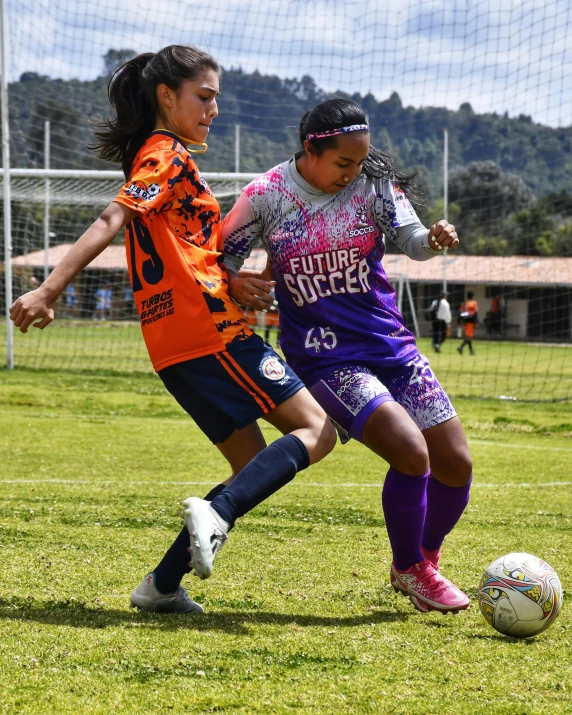 two girls playing soccer, one being tackled by the other