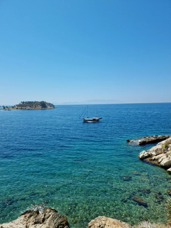 there are two boats in the water next to some rocks