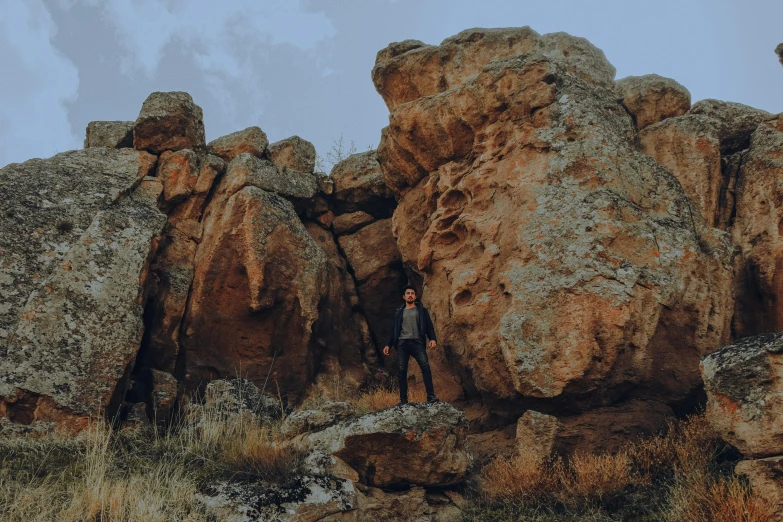 there is a man standing by some big rocks