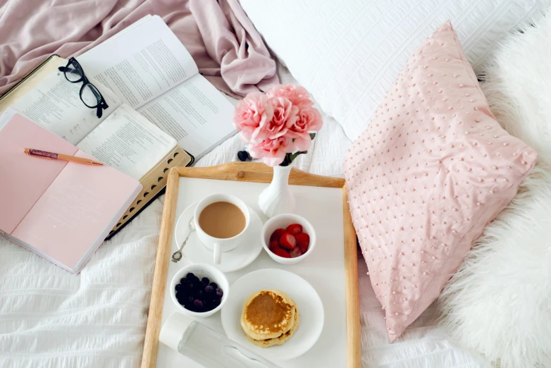 a breakfast tray set on top of a bed with reading material