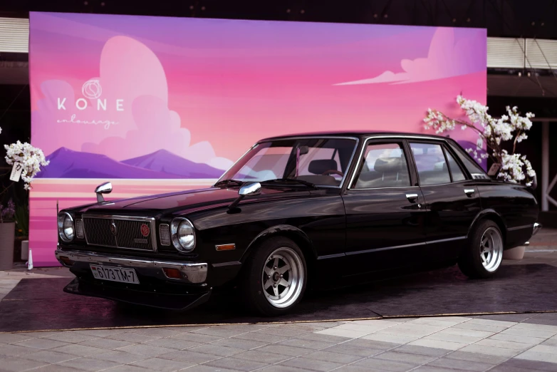 a black car is parked outside of a pink mural