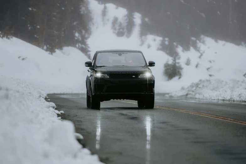 a black car driving down a snowy mountain road