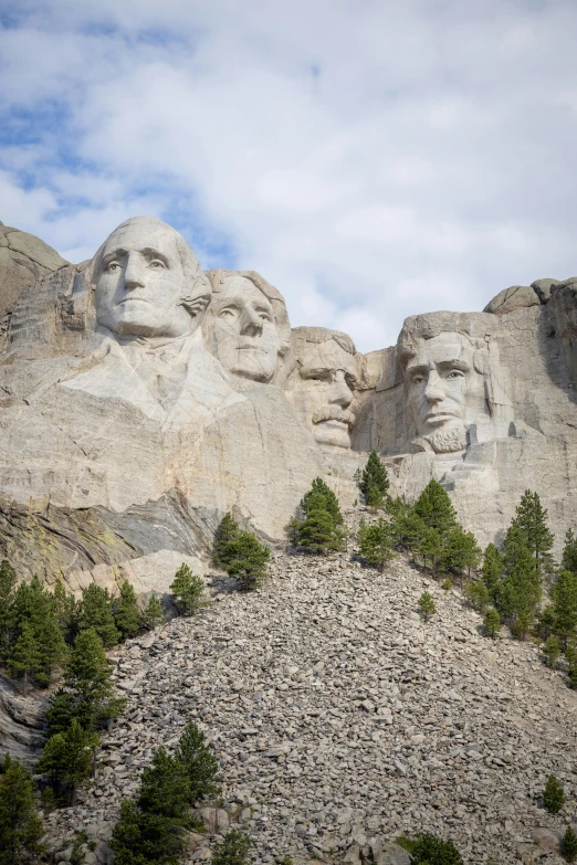 the mount rush monument with trees in the foreground and several large statues of presidents