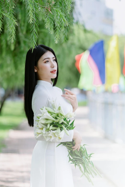 a woman is holding flowers standing under a tree