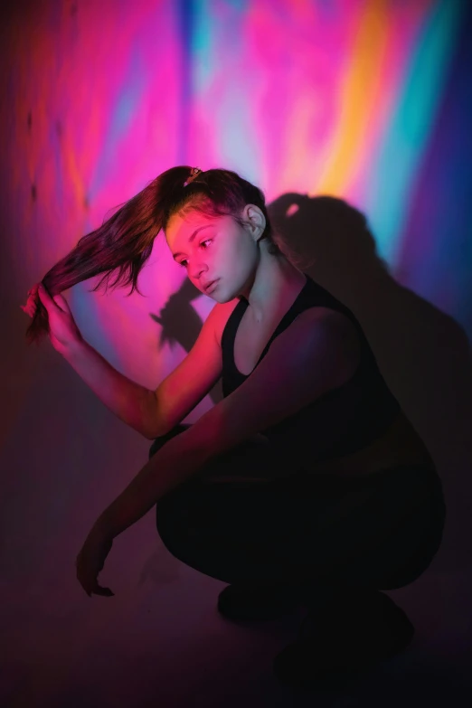a girl kneeling down in front of a rainbow colored background