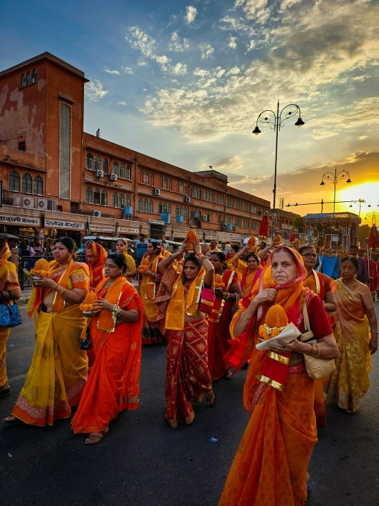 women in orange and yellow saris walking down a city street