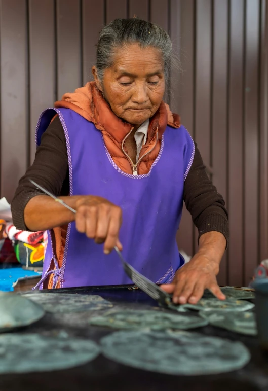 an elderly woman standing over some pots on a table