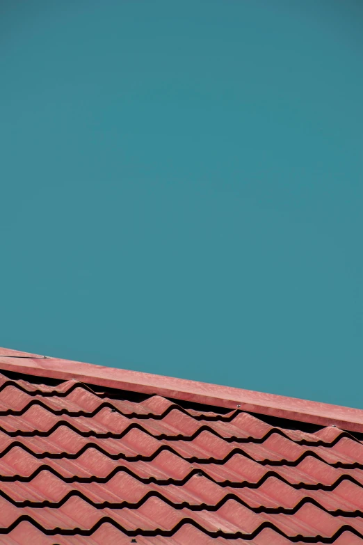 a blue sky and a red roof with a bird perched on it