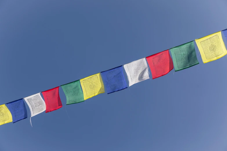 several colorful flags on a line against the blue sky