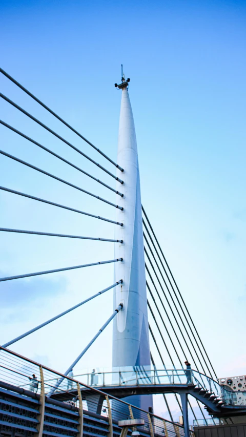 the tall bridge is crossing the water and wires