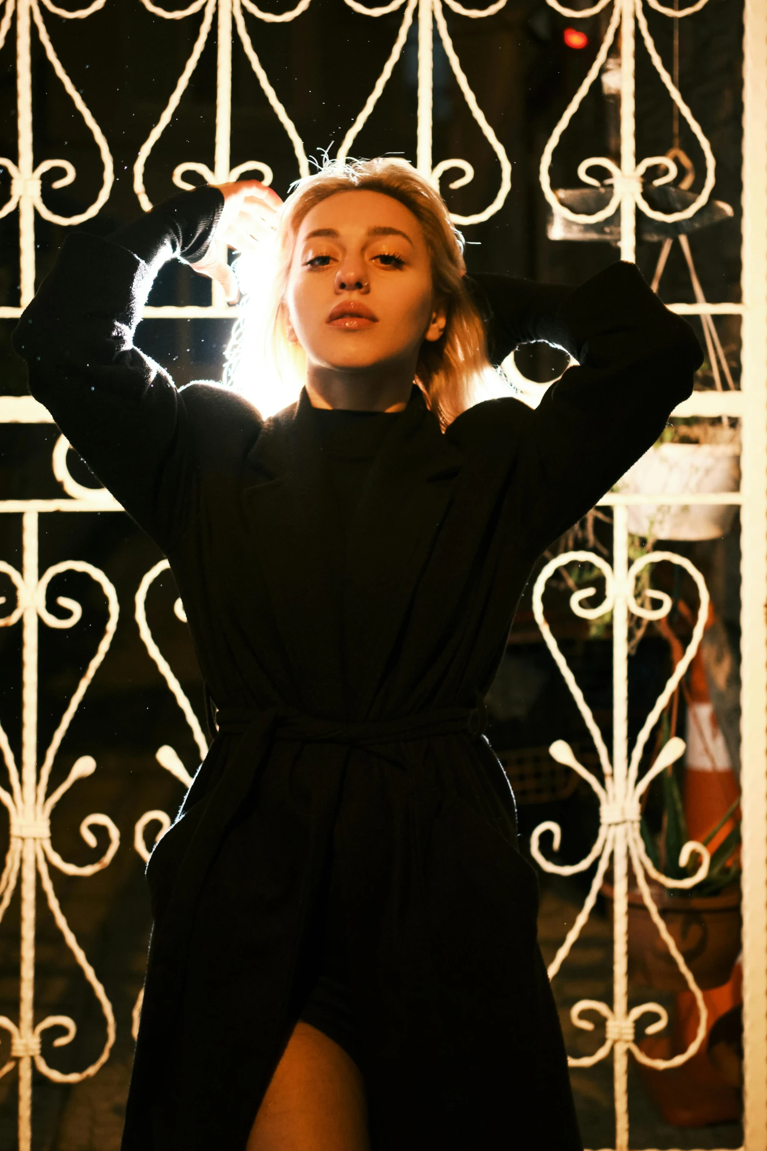 a woman is standing behind an iron gate