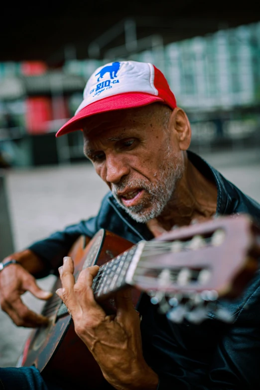 a man with a red cap playing a guitar