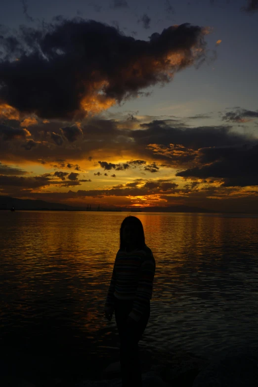 a woman is standing in the water by a large body of water