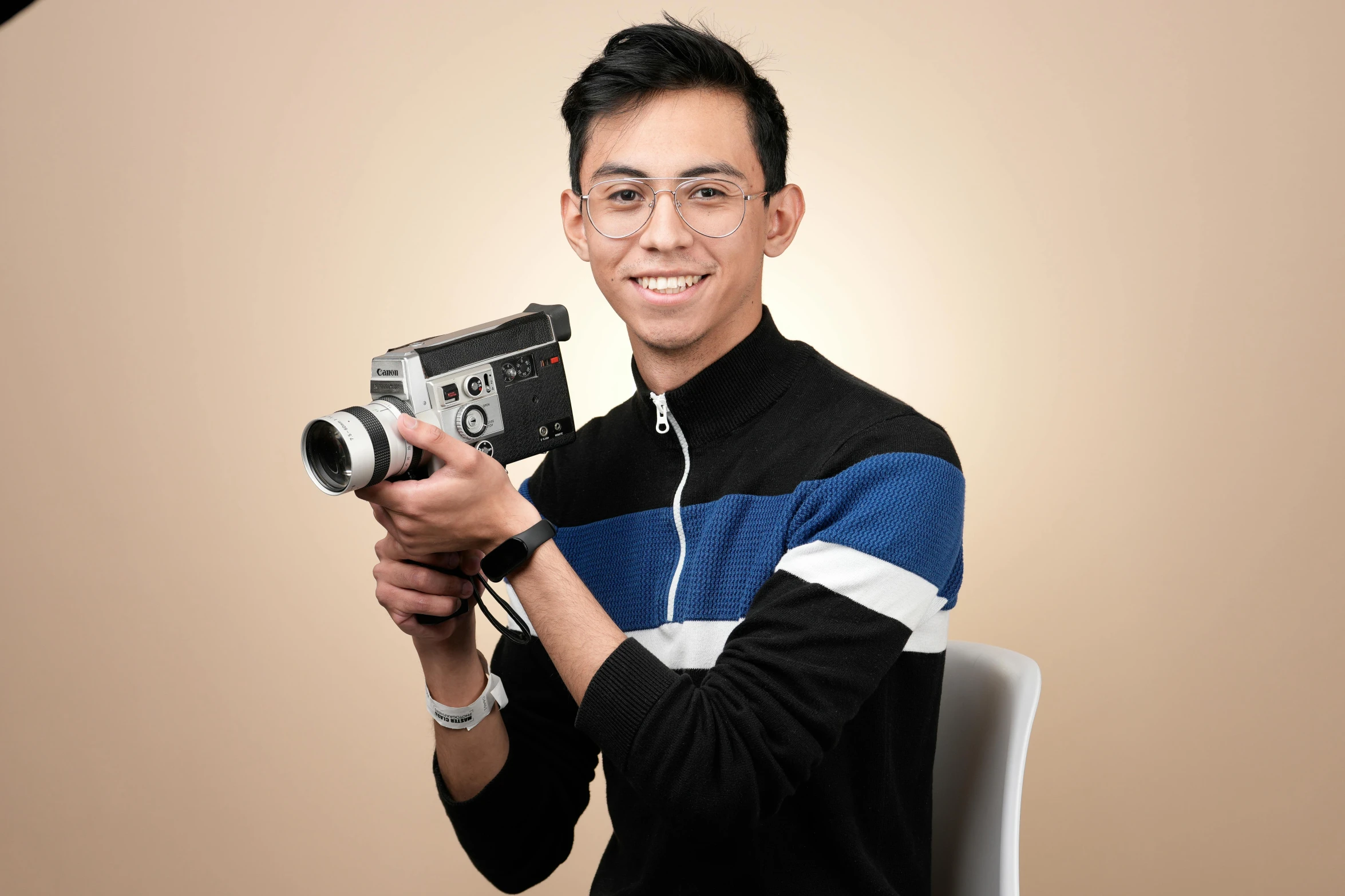 a man is holding up a camera in front of a tan background