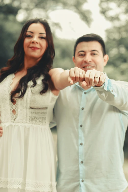 a couple smiling for the camera as they hold their fingers out