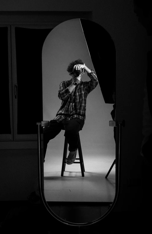 a man sitting on top of a chair next to a mirror