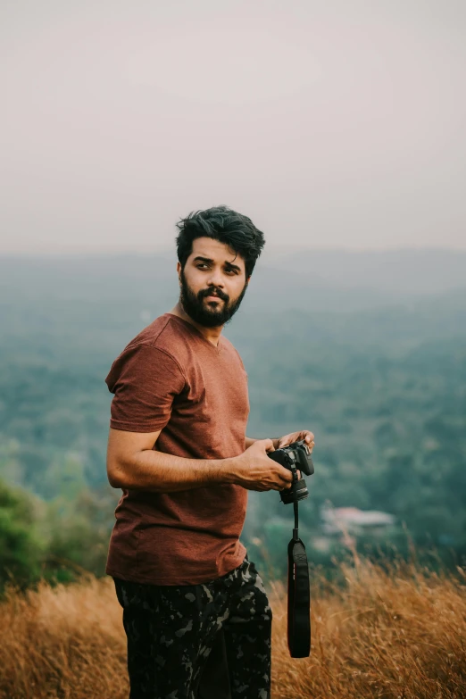 a man standing in an open field with mountains in the background