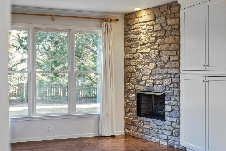 an empty living room with a fireplace and cabinets