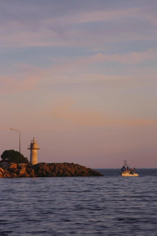small boat sailing on body of water next to lighthouse