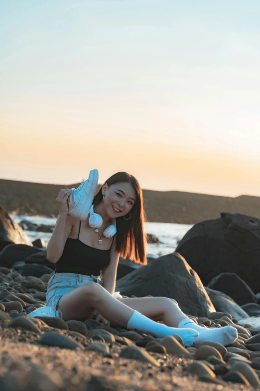 a girl sitting on a beach holding a stuffed animal