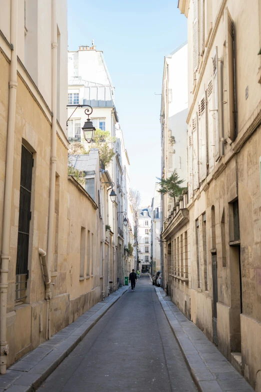 a long narrow street has a couple of people walking along it