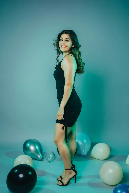 a girl posing in a little dress and black shoes in front of balloons