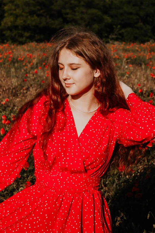 woman in a red polka dotted dress poses in a field of wildflowers