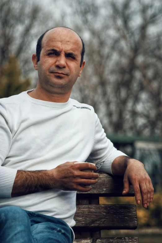 a man in white shirt sitting on top of wooden bench
