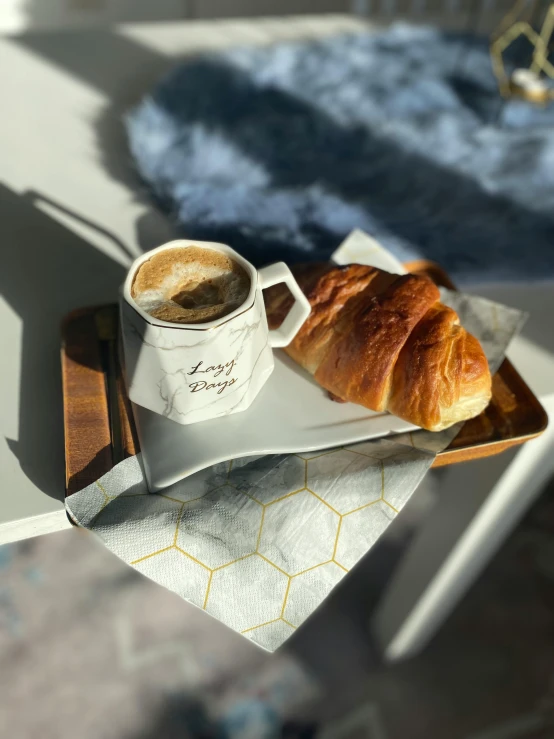 a cup of coffee and a croissant on a tray