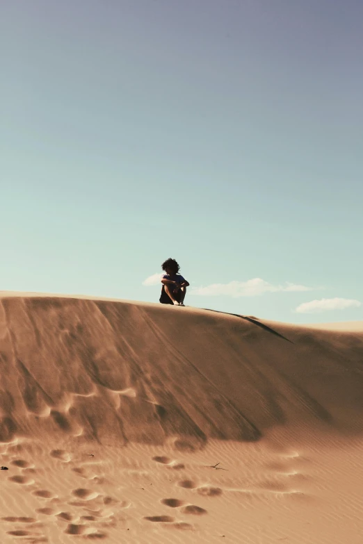 a person sitting on top of a desert dune