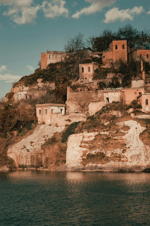 old buildings on the side of a cliff by the water