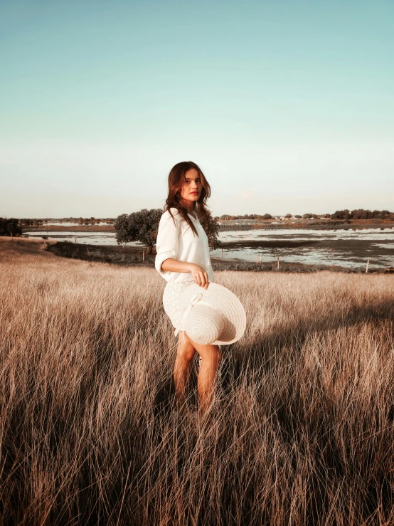 a young woman in an open field looking at the sky