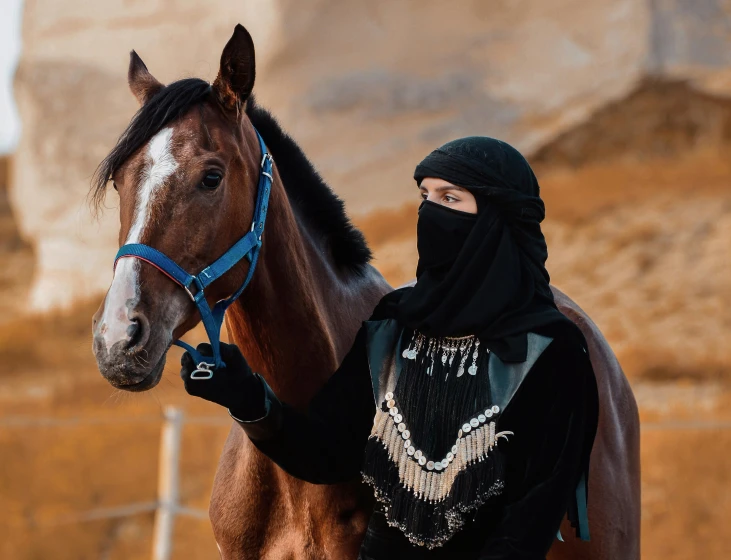 the woman has on a black outfit and is next to a horse