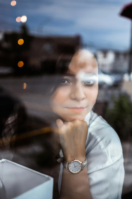 a woman looking out a window with her hand to the side