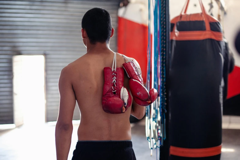 a man in shorts and boxing gloves stands by a punching bag