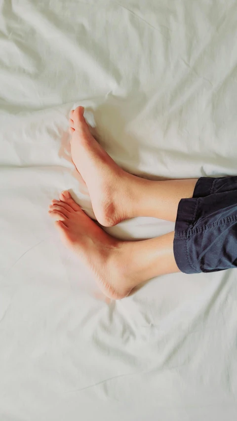 a person with bare legs laying on white sheets