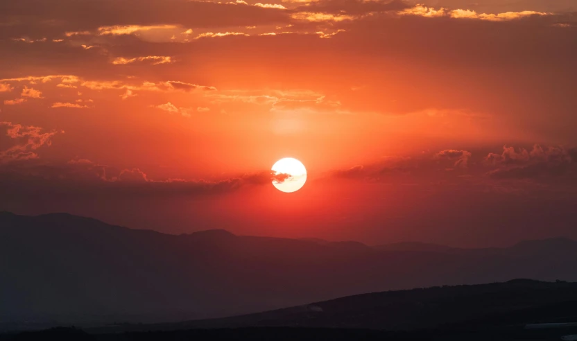 the sun is setting over the hills and mountains