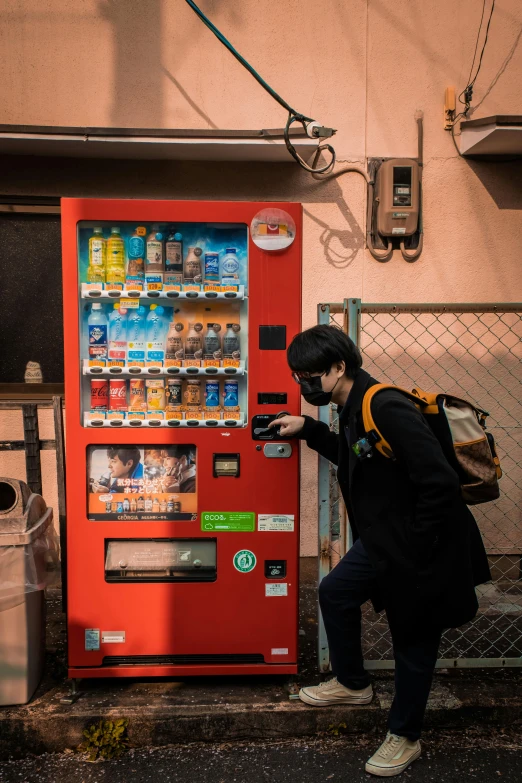man standing near a vending machine on the side of a building