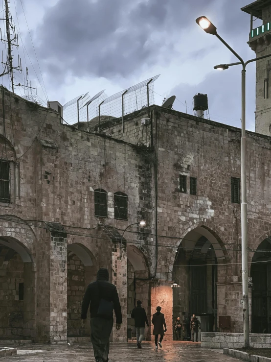 people walking in the street at dusk with a clock tower on the building