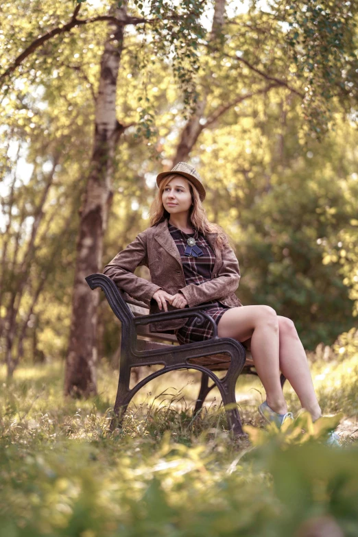 a women that is sitting on a bench in a forest