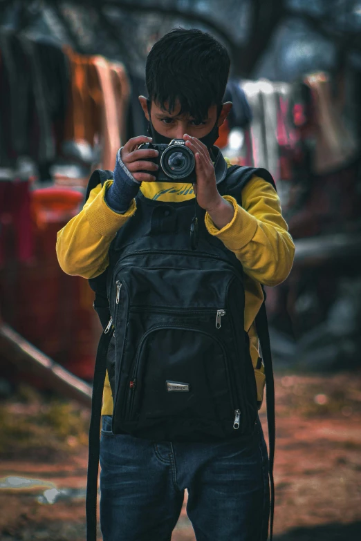 boy taking po of himself with backpack on the street