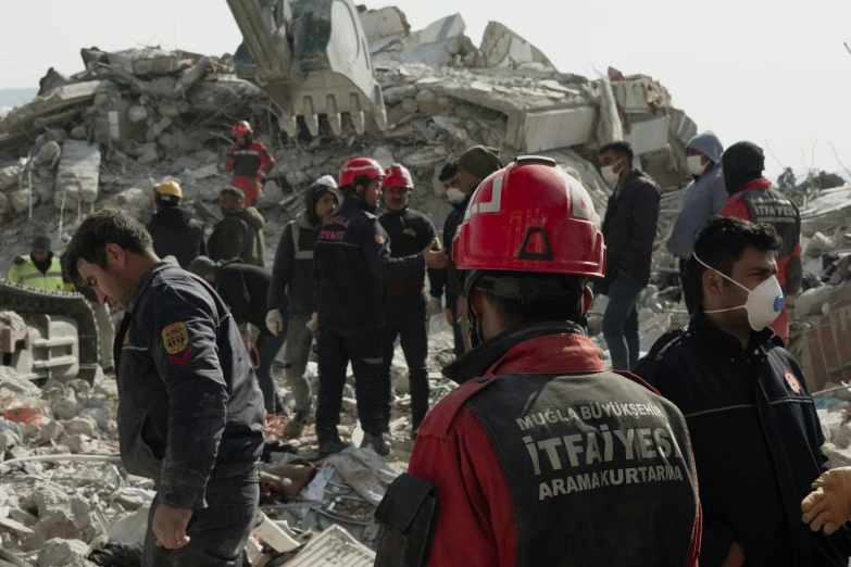 a group of firemen and rescuers working at a rubble pile