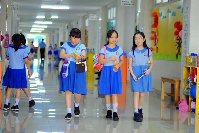 several girls in blue dresses are standing inside a hallway