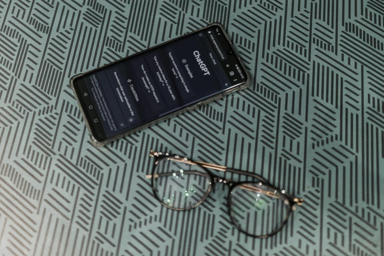 a pair of glasses is laying next to a smart phone on a rug